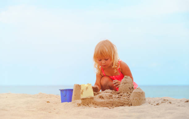 istock cute little girl play with sand on beach 641994114