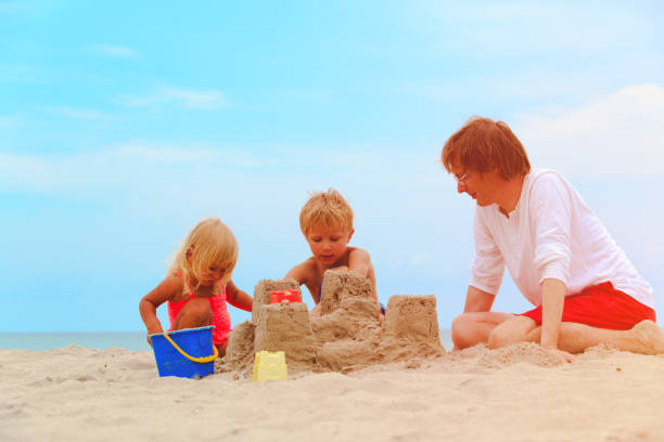 istock father with son and daughter building castle on beach 641994200