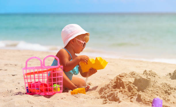 istock cute little girl play with sand on beach 641994414