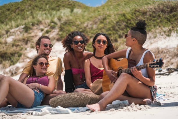 istock Woman playing guitar for friends at beach 641994620