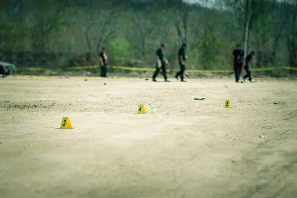 evidence marker with blurred forensic and law enforcement team searching in crime scene training with copy space and cinematic tone