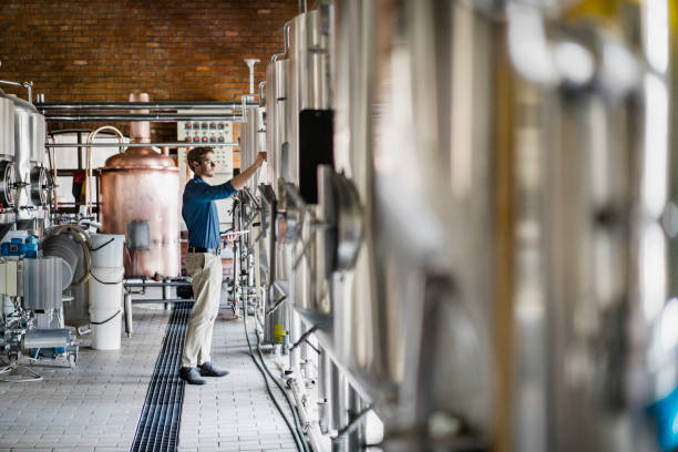 männliche arbeiter bedienen von maschinen in brauerei - distillery stock-fotos und bilder