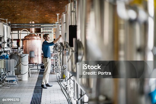 istock Male worker operating machinery in brewery 641999270