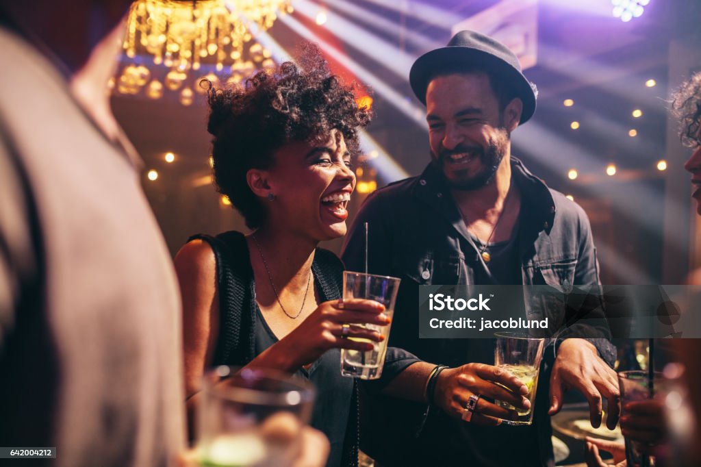 Group of young friends on a night out Group of young friends on a night out at pub. Happy young men and women having drinks and smiling at night club. Bar - Drink Establishment Stock Photo