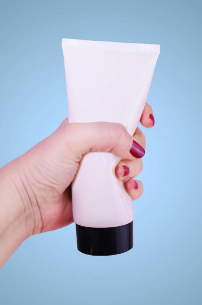 istock Woman´s hand squeezing a white and black body lotion tube. 642006892