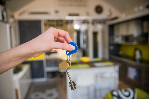 Apartment key in woman hand in closeup view as house rental concept, holding house keys of her new house, real estate and relocation concept