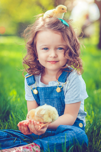 Little girl celebrating Easter outdoors with chicken