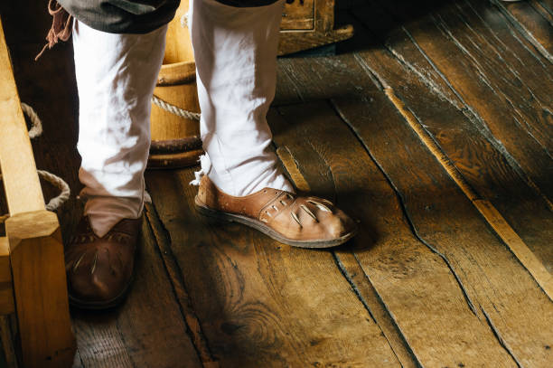 Stratford Upon Avon, UK - August 12, 2015: Man wearing old shoes on a wooden tiled floor in Shakespeare Birthplace Museum. Stratford Upon Avon is a market town and the birthplace of Shakespeare.