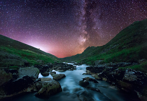 An idyllic night scene taken at Tavy Cleave looking down the river Tavy. You can see the Milky Way Galaxy rising dramatically above the valley. Tavy Cleave is location on Dartmoor National Park and is a renowned area of natural beauty.