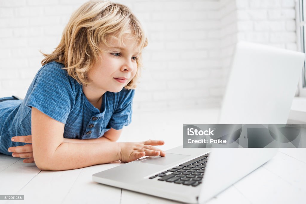 Little boy using laptop Cheerful little boy using laptop at home 8-9 Years Stock Photo