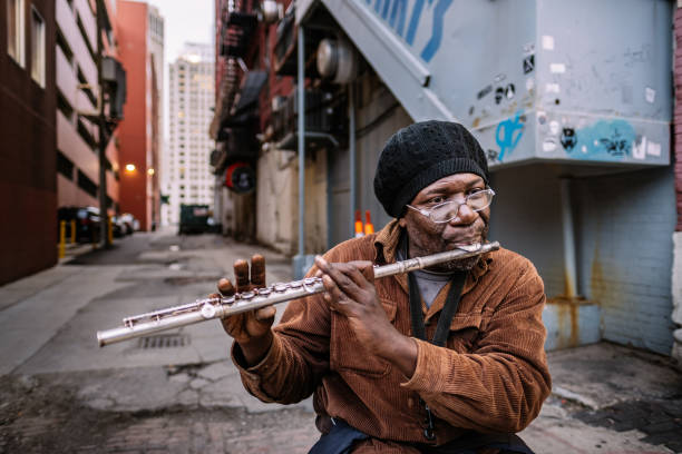 Detroit, Michigan, USA. African-American street performer playing a flute in the alley of downtown Detroit. Evening in the city.