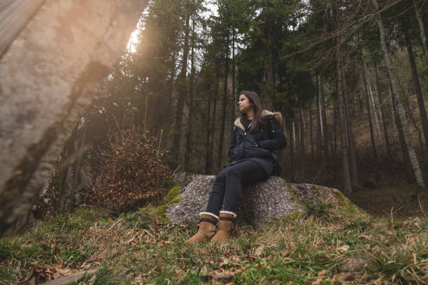 istock Young female explorer sitting on a stump in forest 642014274