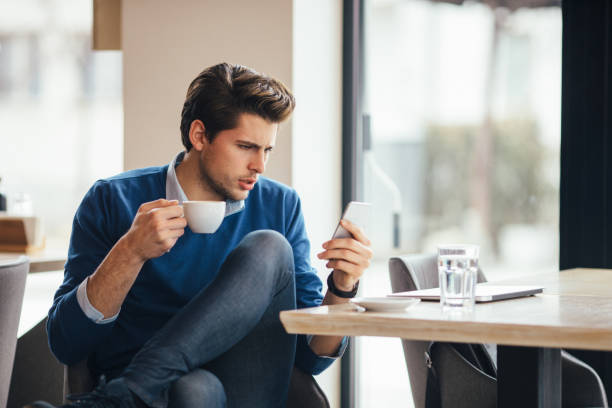 istock Happy young man at cafe using smartphone 642034890