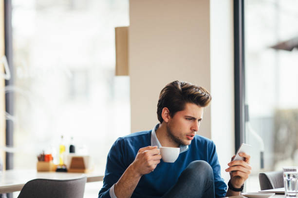 istock Happy young man at cafe using smartphone 642034898