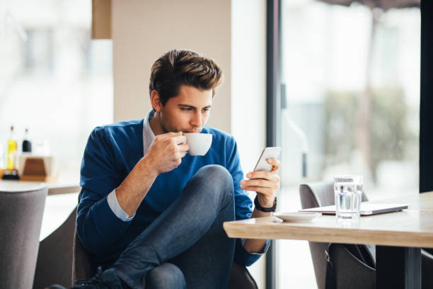 istock Happy young man at cafe using smartphone 642034950