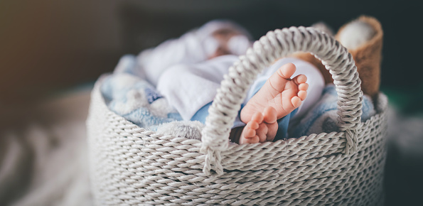 young family of mother of the father and kid. Mother and the father hold legs of the newborn child in the palms.