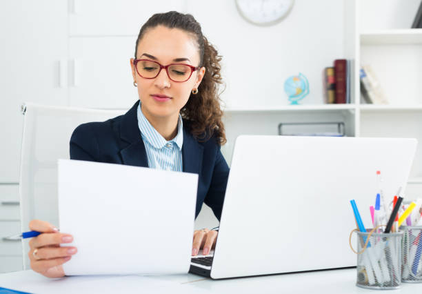 istock Smiling woman working with paperwork and laptop 642053864