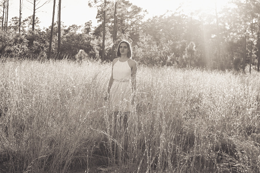 Beautiful young woman in a sunlit field in a black and white image