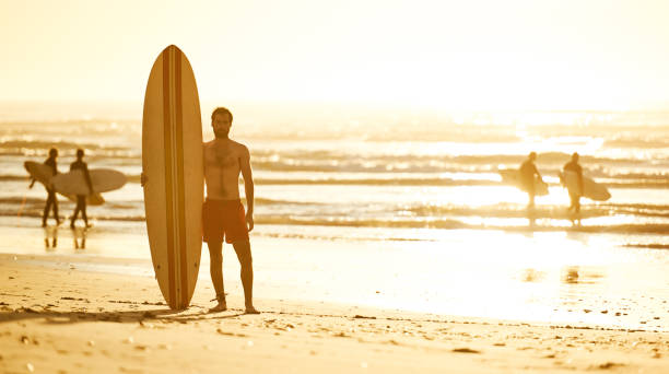 istock Surfer standing on beach with other surfers behind him 642079214
