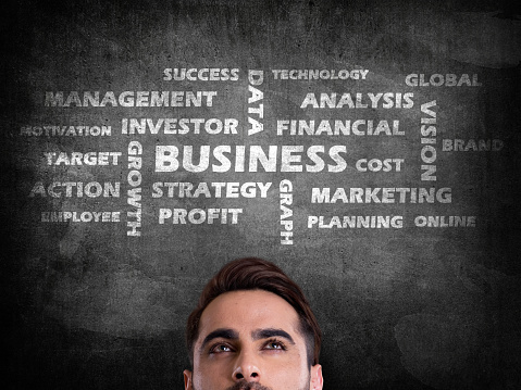 Young businessman in front of blackboard with concept of successful business strategy