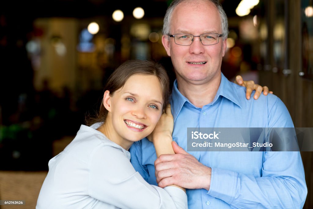 Happy Adult Daughter Embracing Middle-aged Father Closeup of smiling young woman embracing middle-aged man. They are looking at camera. Mature Adult Stock Photo