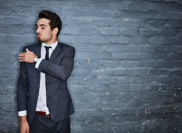 Blowing his own trumpet Shot of a businessman brushing off his shoulders against a grey wall arrogant-business-man stock pictures, royalty-free photos & images
