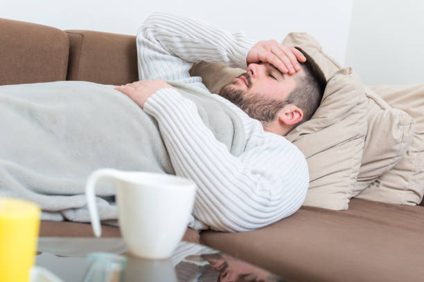 Sick man with flu Young adult sick man with flu lying on sofa man fever stock pictures, royalty-free photos & images
