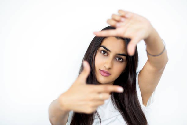 Young Indian woman showing frame hand gesture and looking at camera. Indian female photographer choosing picture area for shooting. She focusing in frame. Occupation concept