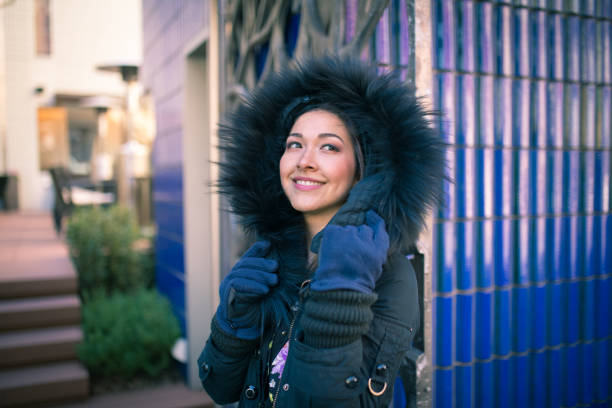 Closeup portrait of attractive young woman wearing warm fur coat in winter.