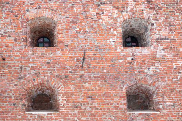 windows in niches on an old brick wall of ancient fortress or prison