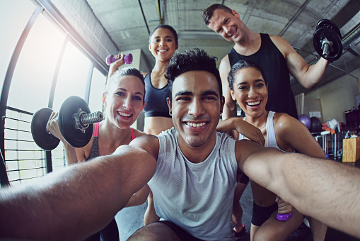 Portrait of a group of happy gym buddies taking a selfie in the gym