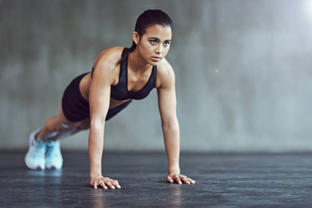 She's at the gym 24/7 Shot of a strong young woman doing pushups alone in the gym push ups stock pictures, royalty-free photos & images