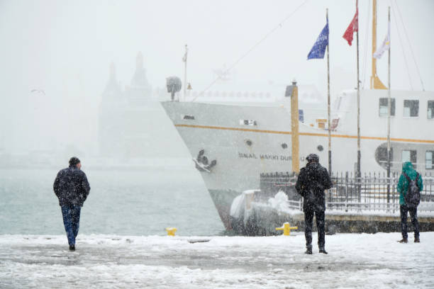 People Are Watching The Scenic At Kadikoy in Snowy Day People are watching the scenic at Kadikoy in a snowy day with a traditional public transportation ship and The Haydarpasa Train Station Building at the background. haydarpaşa stock pictures, royalty-free photos & images