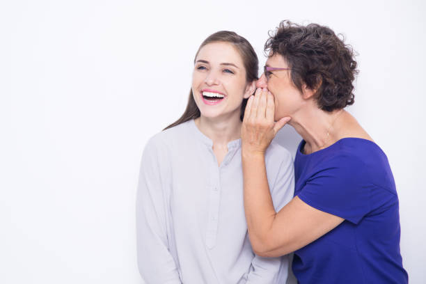 senior mujer susurro secreto de mujer alegre - whispering couple discussion smiling fotografías e imágenes de stock