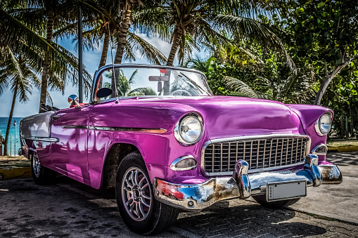 HDR - American pink convertible vintage car parked under palms near the beach in Varadero Cuba - Serie Cuba Reportage