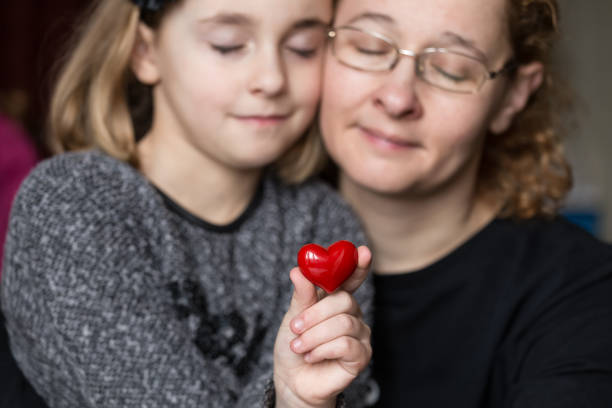 istock Hand holding heart against two people background 642275408