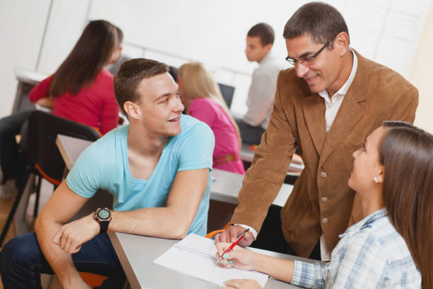 istock Smiling professor assisting students in the classroom. 642279706