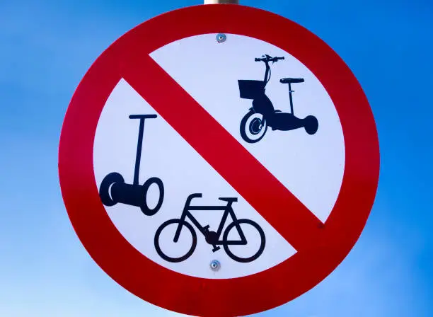 Prohibition road sign - No bicycles, no segway and other motorized vehicles - against blue sky.