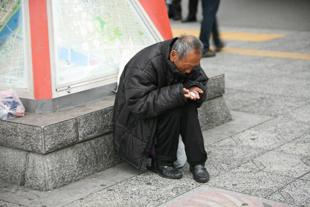 Beggar considers collected alms Токио, Japan - March 22, 2009: Japanese beggar sits on a podium of information curbstone and considers collected alms in Asakusa district, Tokyo. beg alms stock pictures, royalty-free photos & images