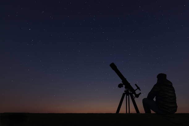 istock Man with astronomy  telescope looking at the stars. 642298798