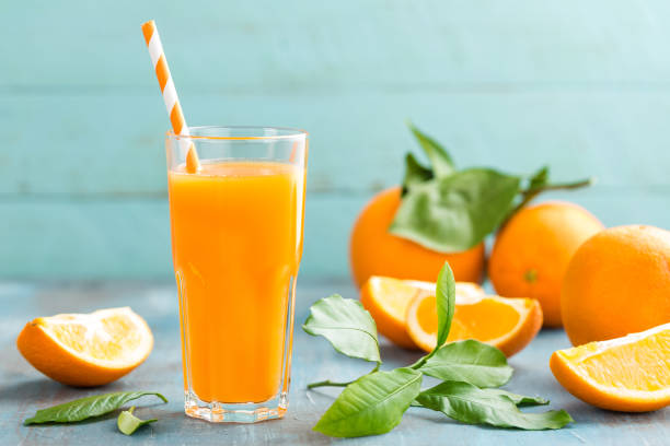 апельсиновый сок в стеклянных и свежих фруктах с листьями на деревянном фоне, витаминным напитком или коктейлем - smoothie fruit orange juice стоковые фото и изображения