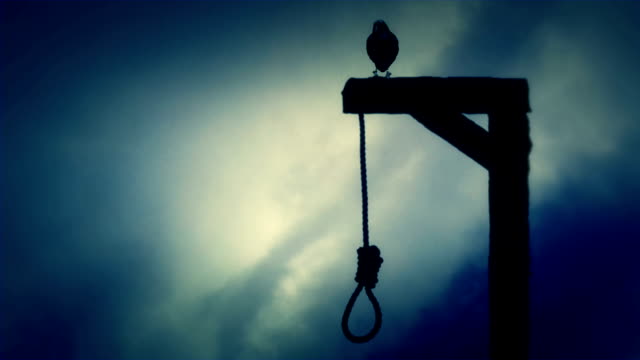 Raven Standing on a Gallows with a Swinging Noose on a Cloudy Day