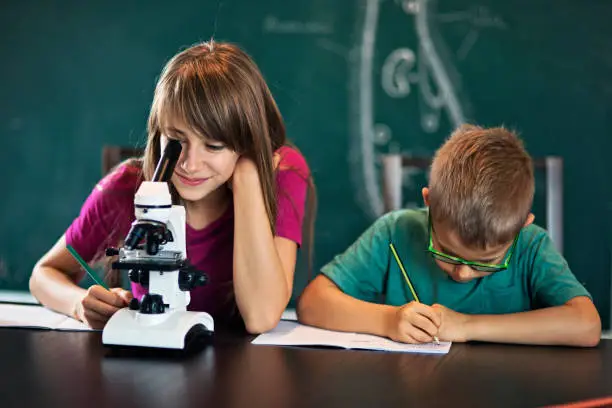 Photo of Boy and girl using microscope on biology lesson