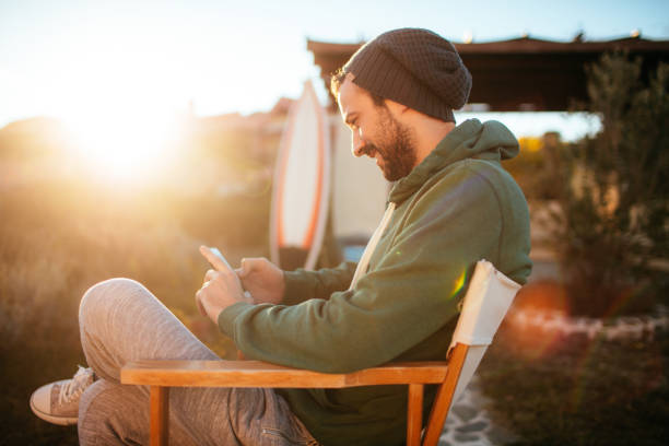 lächelnde surfer mit smartphone - telephone nature mobile phone autumn stock-fotos und bilder