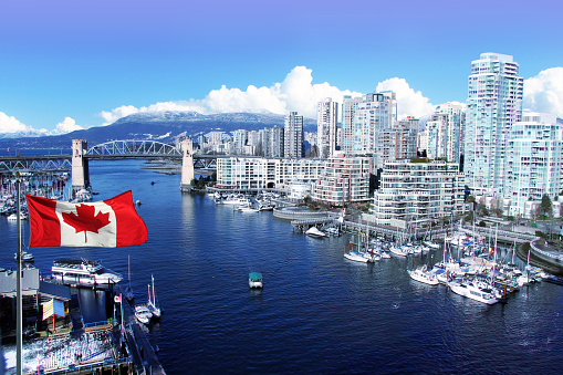 Canadian flag in front of view of False Creek and the Burrard street bridge in Vancouver, Canada.