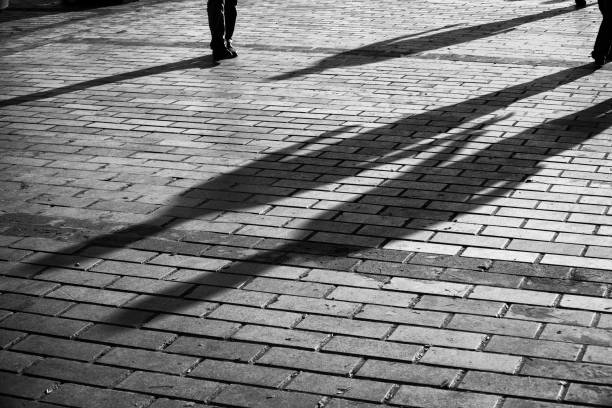 noir et blanc des ombres du peuple sur la surface pavée - paving stone cobblestone road old photos et images de collection