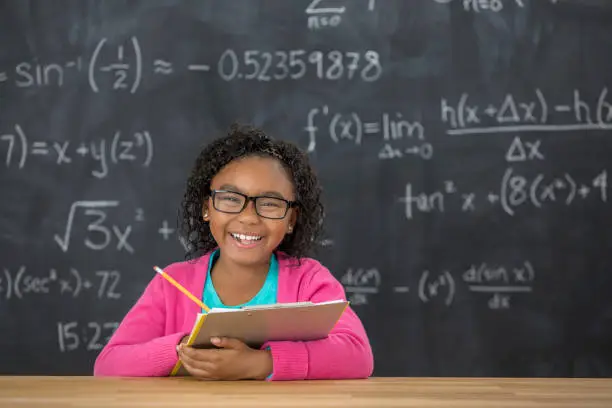 Photo of Happy elementary student with glasses in the classroom
