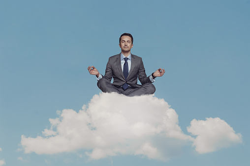 Businessman meditating on cloud