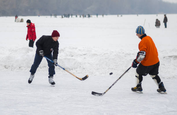 Pareja amateur (hombres jóvenes y maduros) jugando al hockey sobre un río congelado Dnepr en Ucrania - foto de stock