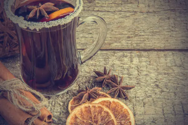 Hot mulled wine, dried oranges, anise and cinnamon on rustic wooden background. Soft toning effect. Vintage style pictures